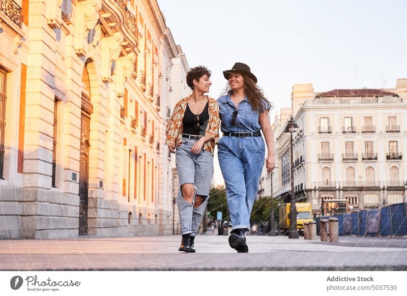 Merry girlfriends walking on street women couple smile weekend date happy madrid spain female young style together positive optimist casual daytime cheerful