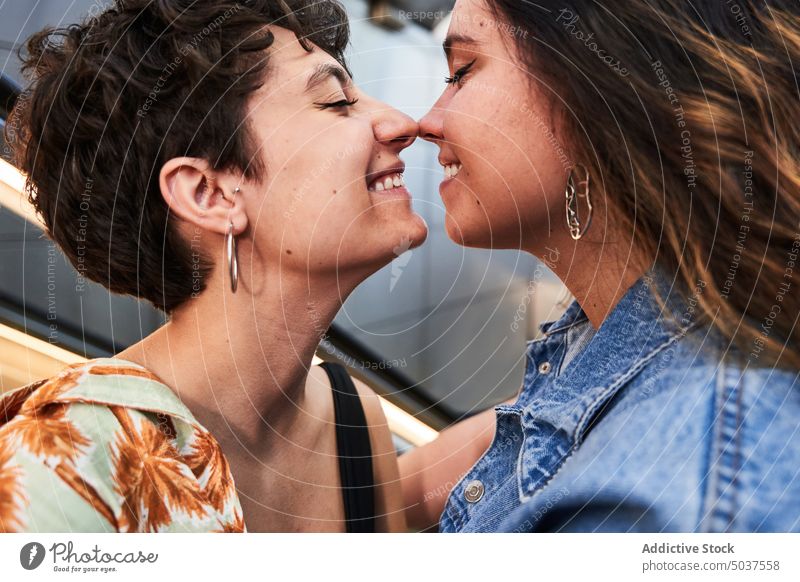 Glad lesbian couple hugging on stairs women touch nose smile urban street underground date madrid spain female young eyes closed girlfriend happy passage