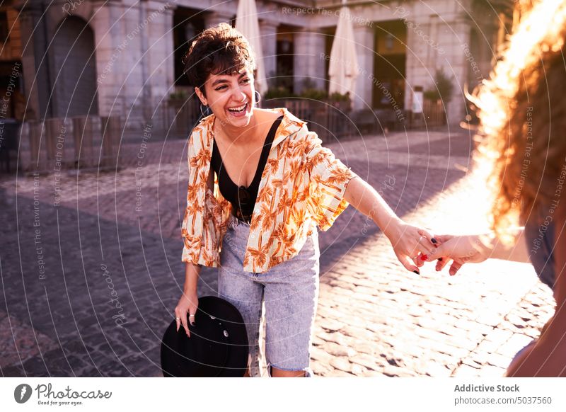 Happy women holding hands on sunlit square couple laugh love romantic weekend together madrid spain female young follow me happy spend time girlfriend sunlight