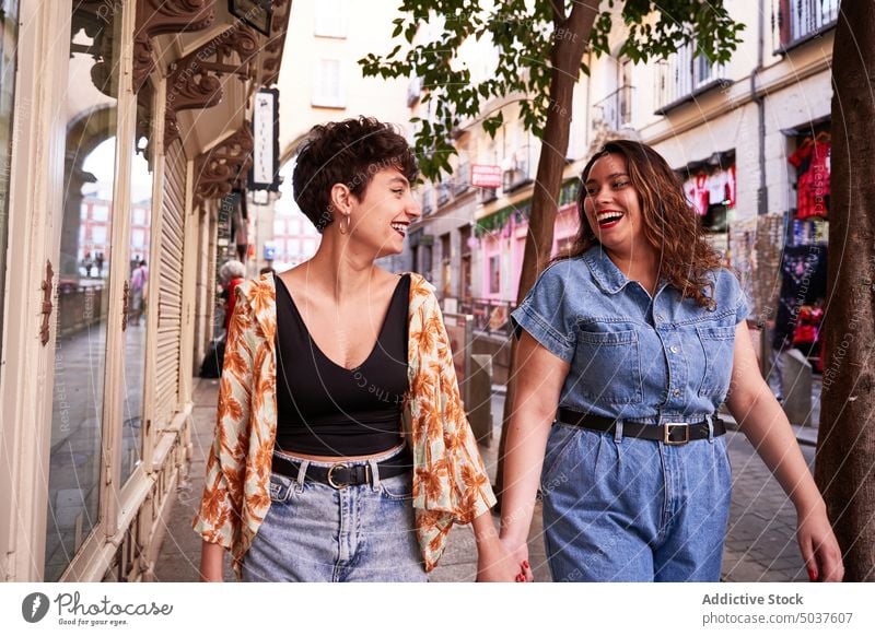 Lesbian couple strolling on street women walk together holding hands smile style lesbian girlfriend madrid spain female young pavement happy positive