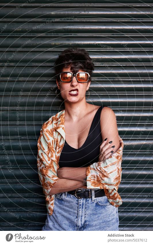 Young brunette looking at camera woman style sneer appearance wall street urban portrait madrid spain female young model sunglasses short hair grimace naughty