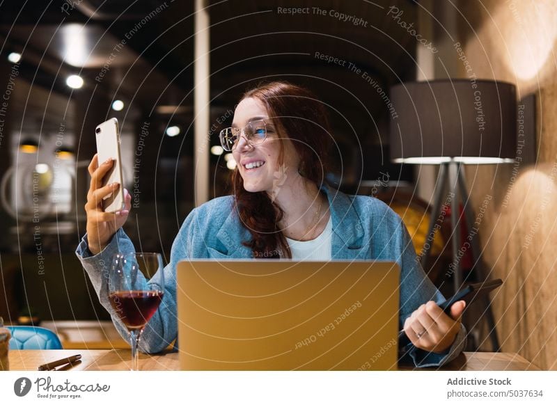 Focused happy female freelancer working in restaurant businesswoman smartphone smile using read data table evening telework analysis delight remote gadget