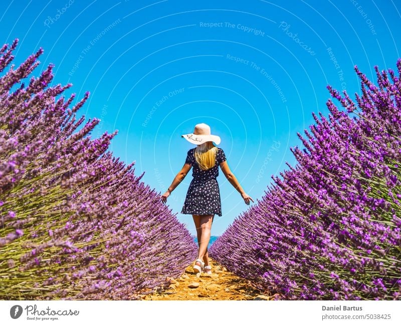 Close up of a young girl in a floral dress with a hat on her head between lavender in southern Provence Valensole France beautiful beauty bloom cheerful
