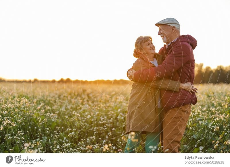 Senior couple in a field in autumn at sunset walking trip backpack senior couple woman two people mature together old retired joy love happiness adult female