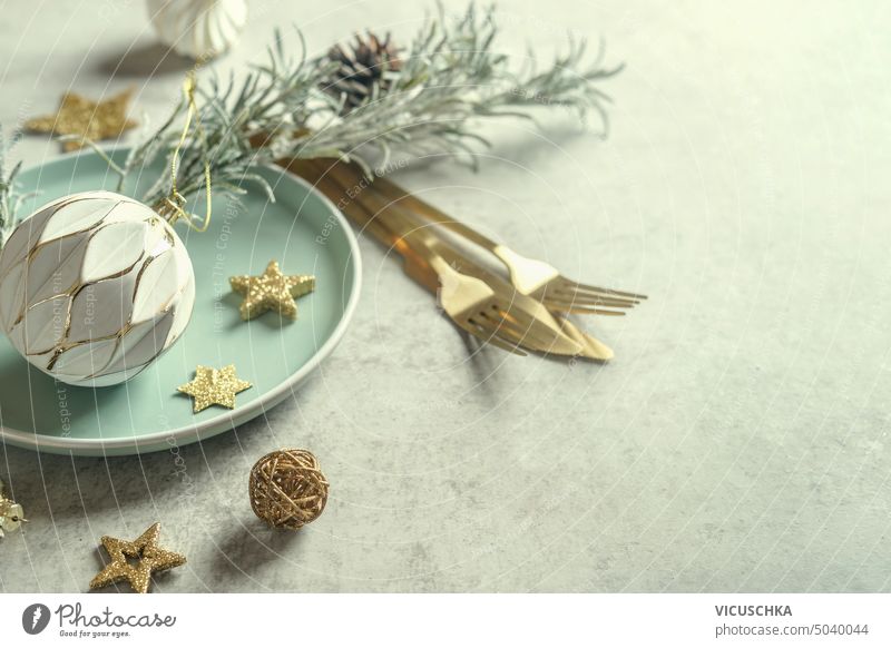 Christmas table setting for vestive dinner with plate, golden cutlery and decoration of vintage bauble, stars and pine branches holiday christmas festive