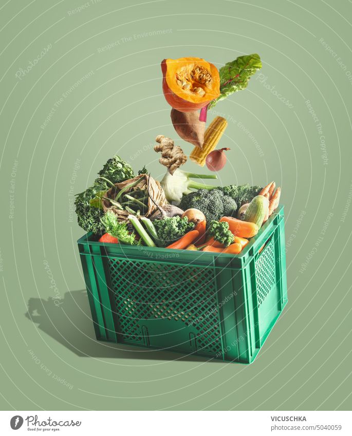 Fresh organic vegetables falling in green box at green background. Food box delivery. Levitation fresh food box levitation carrot copy space fruit grocery