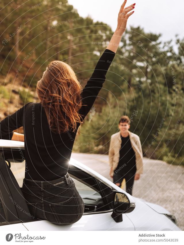 Woman outside open car window waving at man woman wave boyfriend together freedom travel trip countryside greeting couple love sit girlfriend vehicle casual