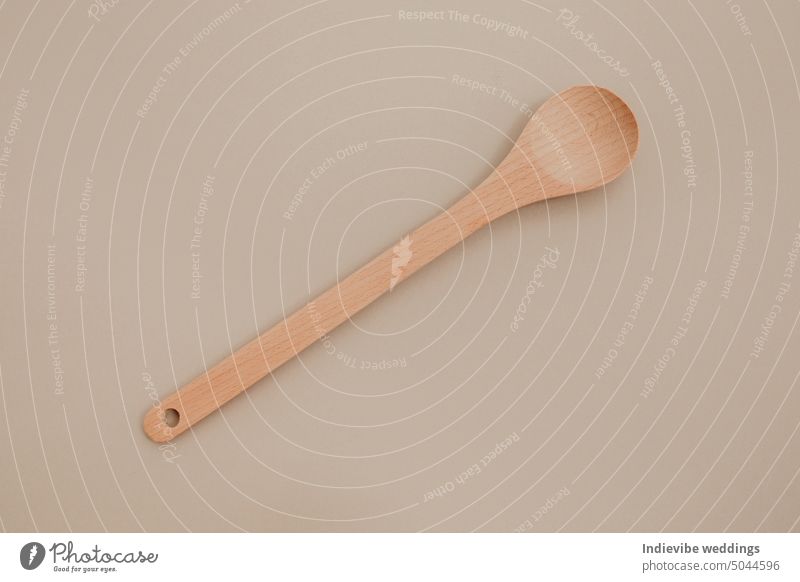 A wooden spoon on beige paper background. Copy space, flat lay photo. isolated brown copy space cooking tool kitchenware spatula utensils equipment spoons