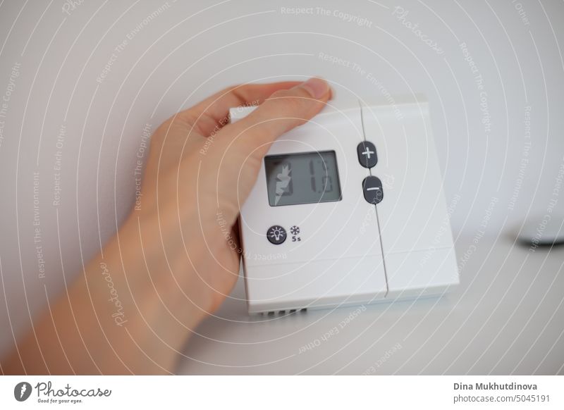 hand holding thermometer showing temperature in the room. Extreme hot temperature on screen of home thermostat. Climate change effect with extreme heat. control