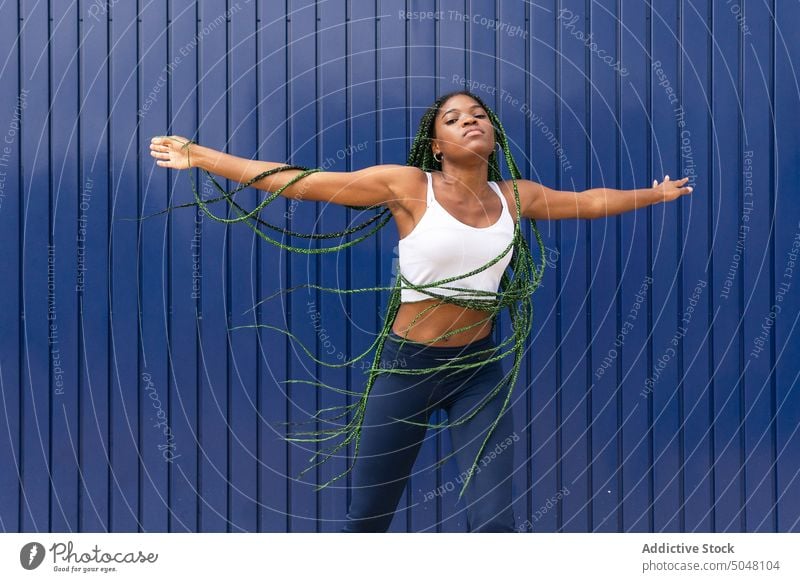 Young dynamic black woman dancing on street dance cool freestyle hip hop urban trendy individuality braided hair motion energy dancer modern wall self assured