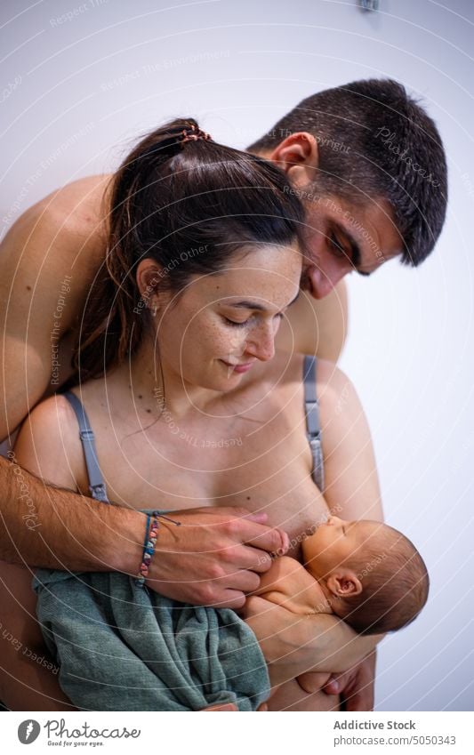 Embracing family with newborn baby father mother infant brestfeeding embrace tender gentle hug together care parent love affection child relationship bonding