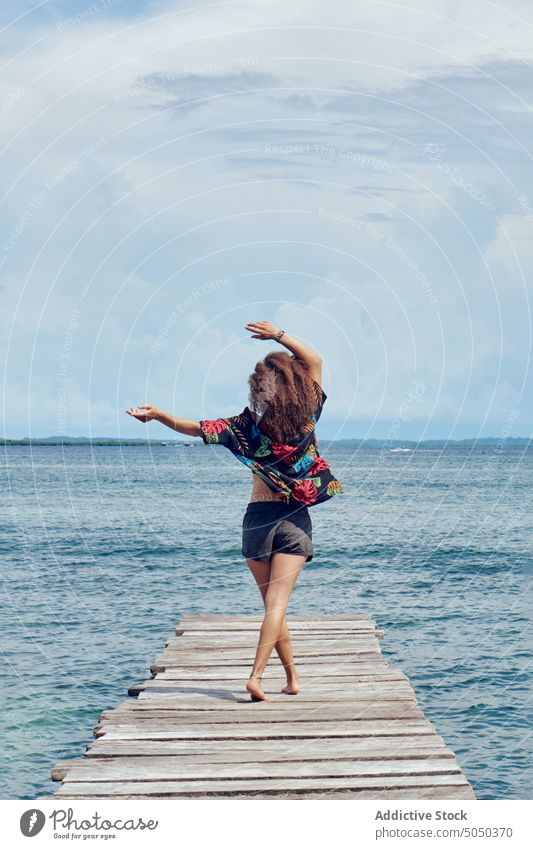 Anonymous woman standing on pier of sea freedom enjoy relax alone carefree seascape summer vacation nature seashore serene long hair seafront seaside water wave
