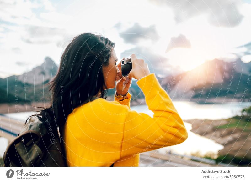 Woman with backpack taking photo of picturesque highlands woman photographer traveler take photo photo camera mountain lake nature tourist female journey device