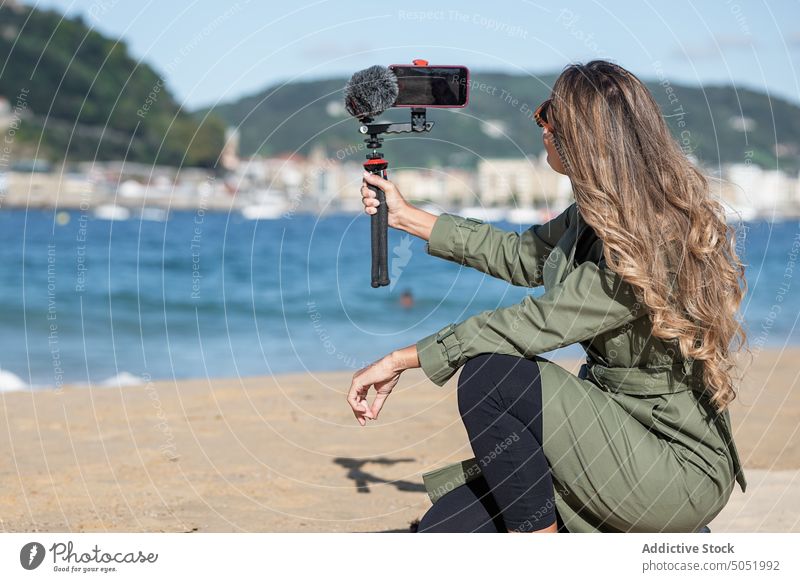 Woman recording on camera with mic on beach woman video vlog take photo device microphone sea city vlogger selfie influencer photo camera broadcast photographer