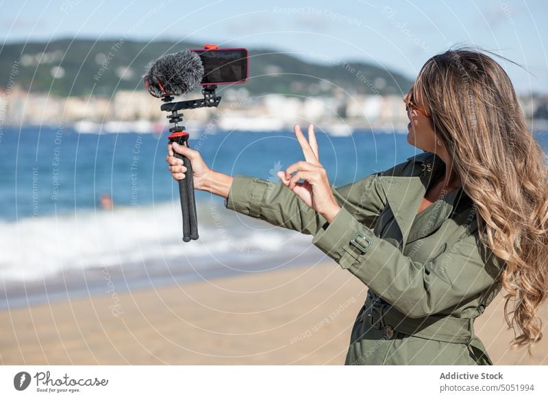 Woman recording on camera with mic on beach woman video vlog take photo device microphone sea city vlogger selfie influencer photo camera broadcast photographer