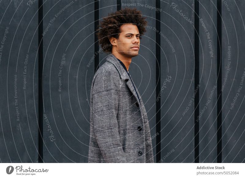 Stylish black man on street style wall smart casual jacket curly hair serious appearance modern male young african american ethnic building cloth apparel