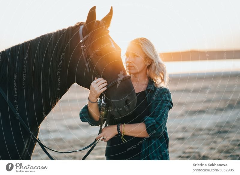 Portrait of adult woman with beautiful horse in nature. Sunlight, silhouette.Concept of love for lesser brothers, caring and animal training outdoor equestrian