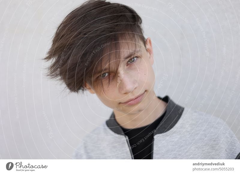 Handsome young man with stylish haircut. Portrait of teen boy with youth hairstyle is standing on grey background and looking at camera. face handsome lifestyle