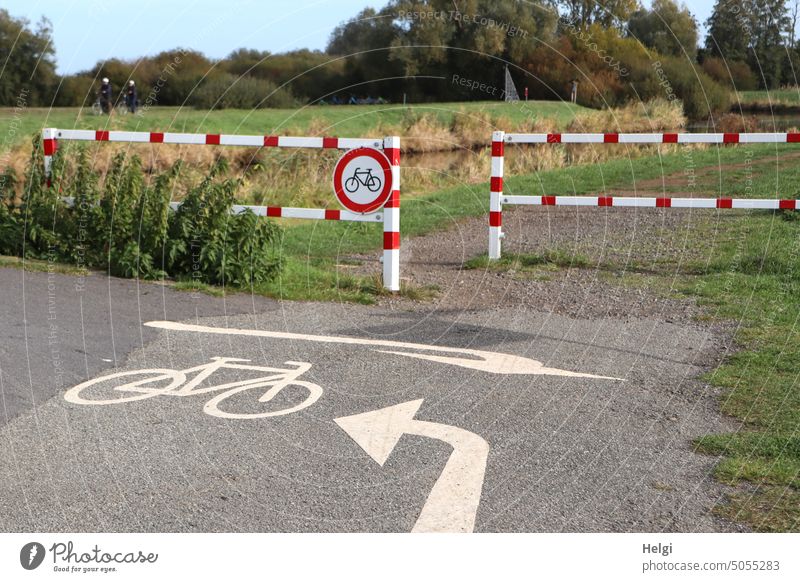 left or right , but not straight ahead - bicycle lane with directional markings and prohibition sign on the red and white fence. cycle path Road sign