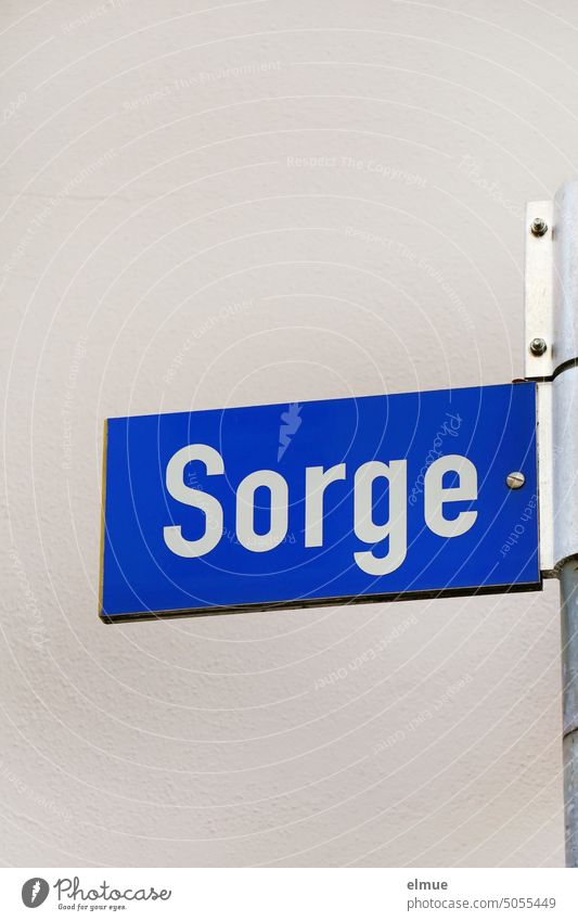 blue street name sign - Sorge - on a metal bar in front of a light wall Street sign Concern Worries street sign Orientation address dwell Signs and labeling