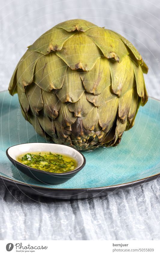 cooked artichoke on a blue plate Artichoke seethed Blue Plate Dip Dressing Chimichurri Eating freshness marinated serve Italian salubriously Nutrition Meal