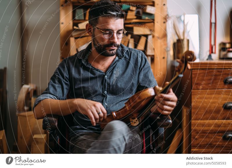 Male luthier with violin in workshop man instrument handicraft studio professional classic workplace craftsman check quality artisan manual master occupation