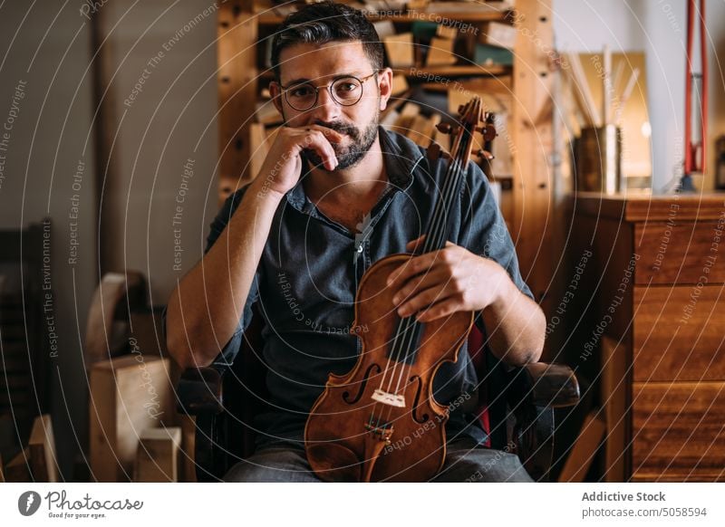 Male luthier with violin in workshop man instrument handicraft studio professional classic workplace craftsman check quality artisan manual master occupation