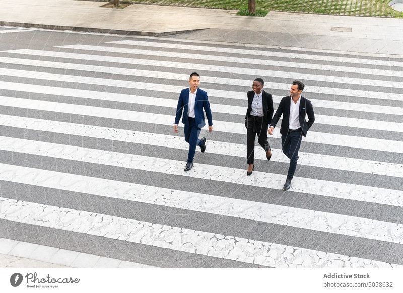 Multiethnic coworkers walking on crosswalk businesspeople colleague cheerful street pedestrian zebra road chat communicate formal diverse city urban multiethnic