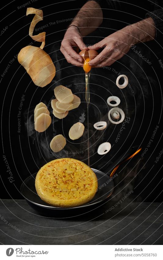 Unrecognizable chef cooking omelette on dark background ingredient potato recipe egg fall onion culinary prepare break mix food photography advertise add
