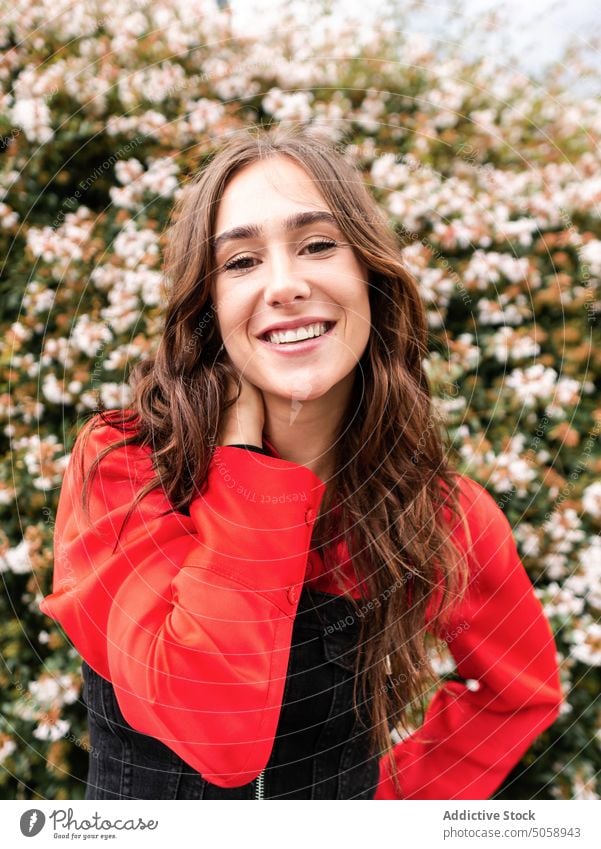 Stylish female near blooming bush woman style street flower urban modern spring appearance confident young brunette outfit shrub blossom individuality daytime