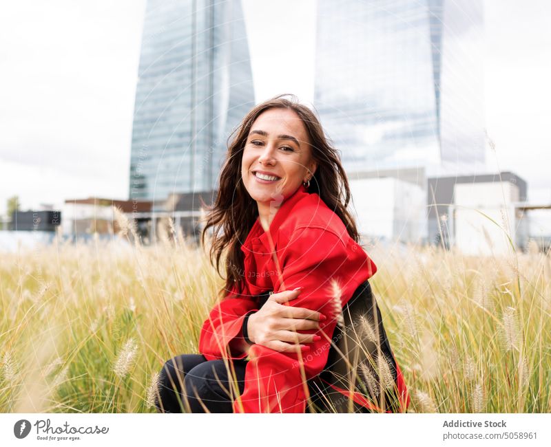 Stylish happy woman sitting in grass in park style urban city haunch summer weekend female young lawn brunette daytime lifestyle personality season