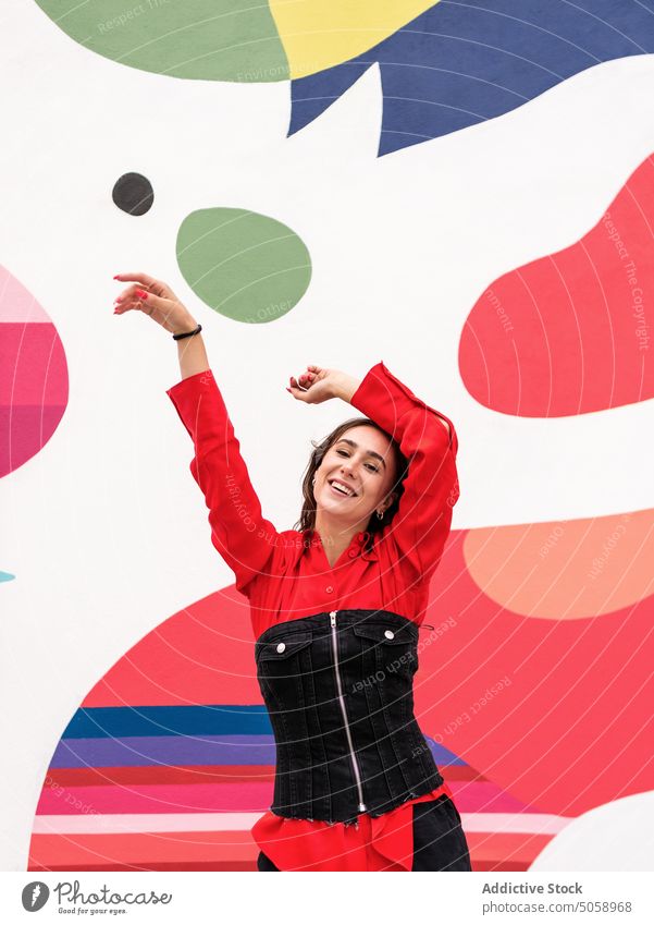 Happy woman dancing against colorful wall dance street style happy urban cheerful modern female arms raised individuality building move positive bright ornament