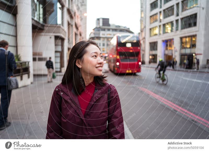 Cheerful Asia woman on city street walk smile sidewalk tourist happy outerwear admire evening london england united kingdom uk female young asian ethnic