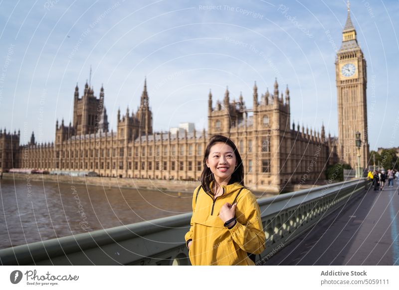 Asian woman on bridge over river smile tourist happy visit explore weekend landmark london uk united kingdom england big ben palace of westminster thames
