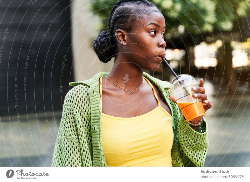 Young black lady drinking juice and smiling in park woman takeaway style confident refreshment to go female young african american ethnic braid street city