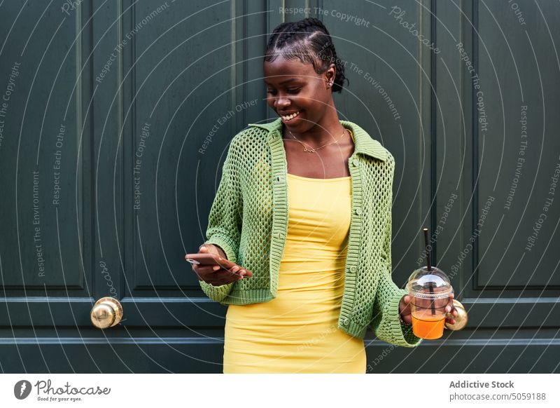 Stylish young ethnic female millennial using smartphone on street woman message confident drink style takeaway cool beverage online internet african american