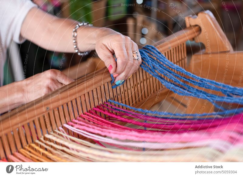 Unrecognizable artisan working with yarn on loom craftswoman thread handicraft weave atelier reed slit studio workshop small business creative colorful