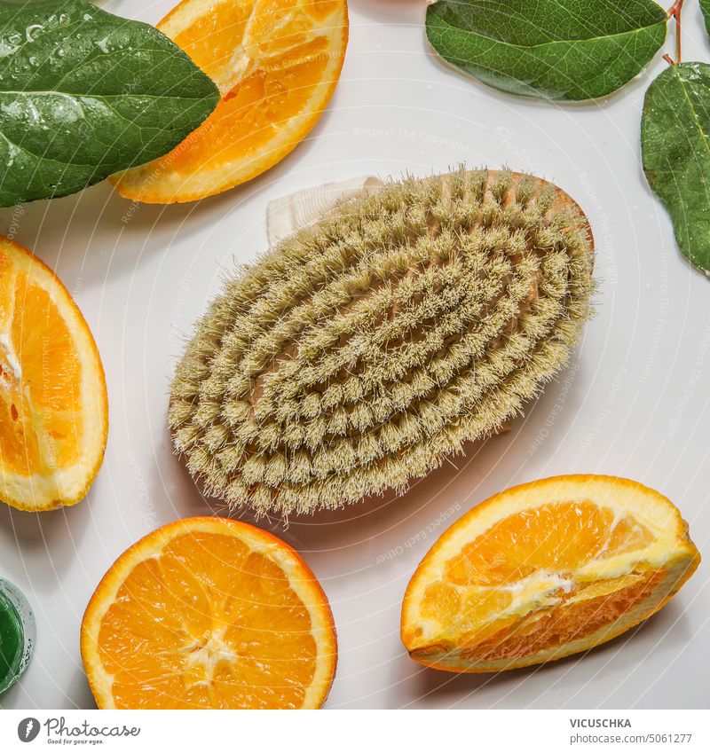 Body care massage brush and orange fruits slices with green leaves on white background , top view body care cellulite treatment bath beauty citrus essential