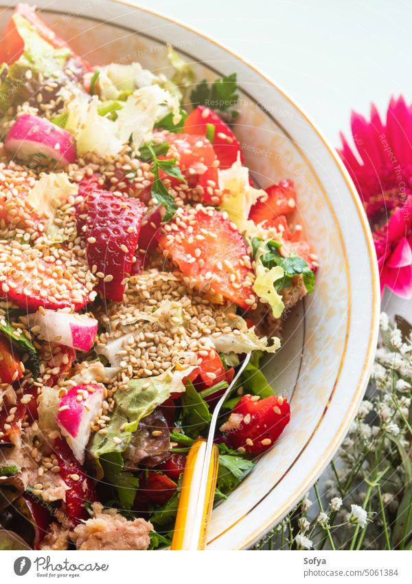 Fresh summer healthy fiber protein vitamin salad in bowl with strawberries, lettuce, tuna, tomatoes strawberry vegetable fruit spring meal fresh green red