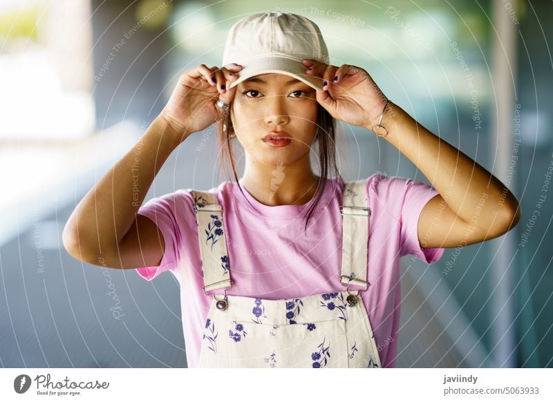 Stylish Asian woman adjusting hat style touch hat cap urban street appearance casual portrait female young asian ethnic individuality personality garment