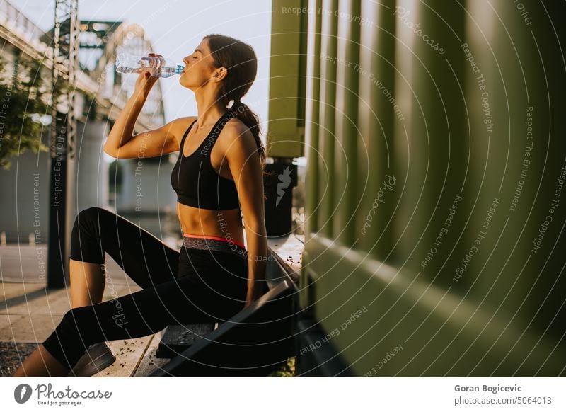 Pretty young woman  taking a break during exercising outside and drinking water athletic caucasian city exercise female fit fitness health healthy horizontal