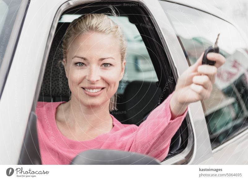 Portrait of responsible female driver holding car keys in her hand. Safe and responsible driving school and concept. woman automobile window teenager smile