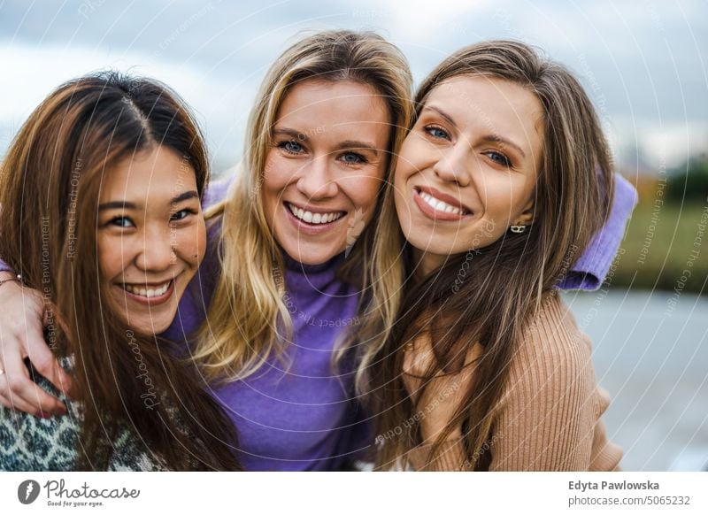 Three female friends hugging each other real people candid woman girls young adult friendship girlfriends girl power fun city urban city life youth millennials