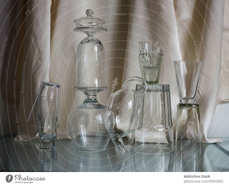 Collection of different glass shapes stacked in a balanced composition transparent glassware still life minimal natural daily light casual beauty dark grey