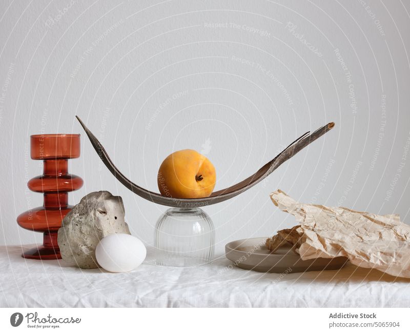 Arrangement with handmade sculpture and a peach still life design fruit shape egg glass stone ceramic object texture fabric textile wrinkles balance arrangement