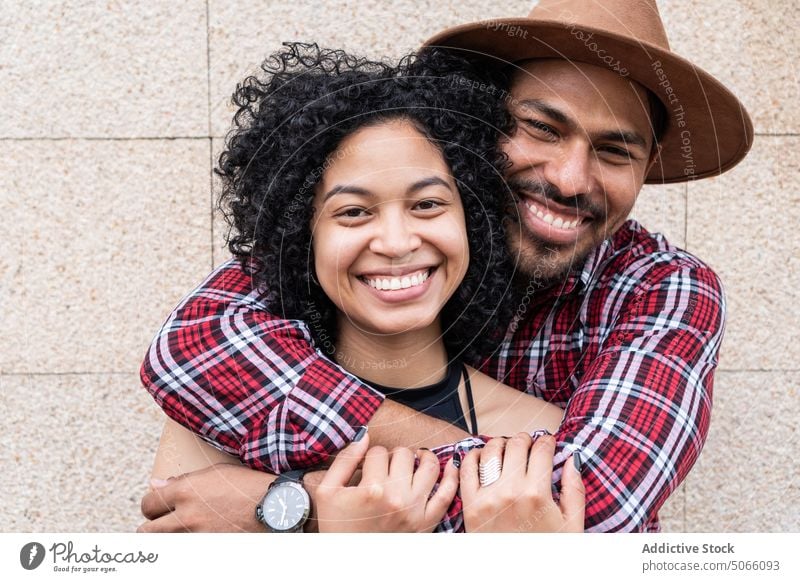 Happy Hispanic couple hugging near wall street love together relationship smile happy portrait daytime glad affection embrace girlfriend boyfriend cheerful