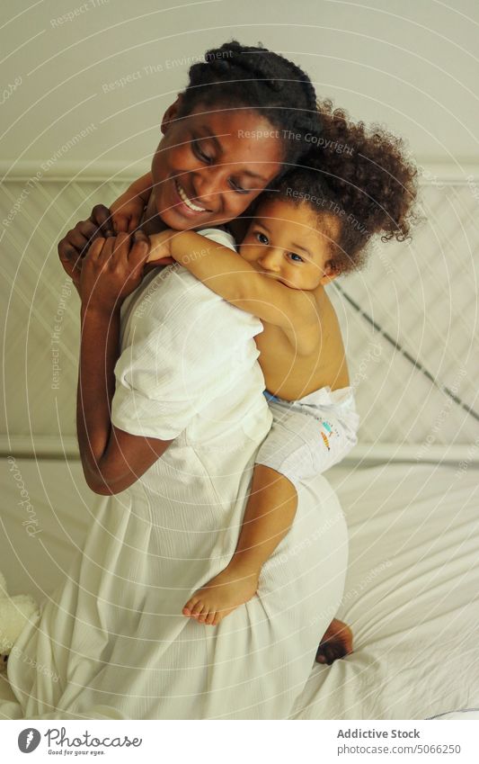 Happy black mother carrying girl on back daughter piggyback love home child bed relationship woman smile spend time happy ethnic african american play