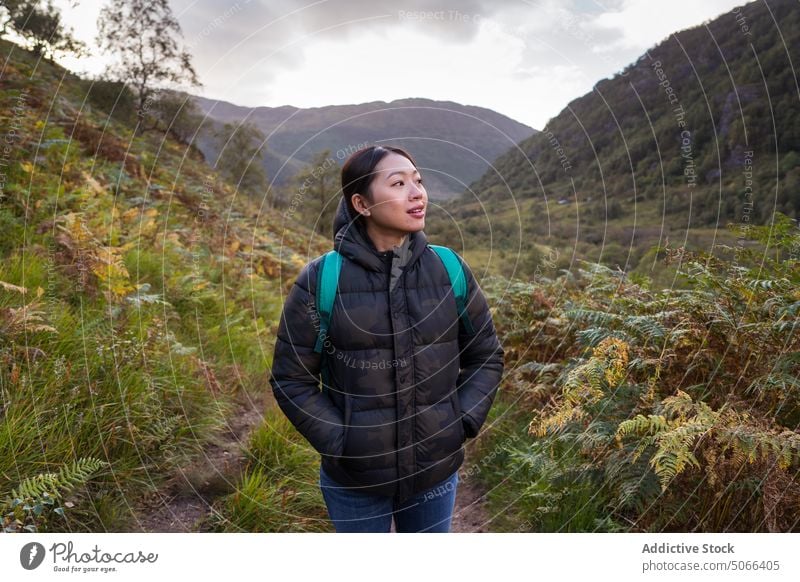 Asian hiker exploring valley and mountains woman walk explore amazed path autumn countryside scotland scottish highlands united kingdom uk female young asian