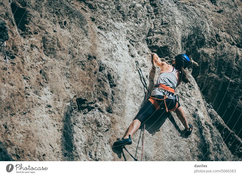 Woman climbing a rock with extreme effort in a vertical rock wall active activity adventure andalusia athletic austrian cliff climber committed endurance