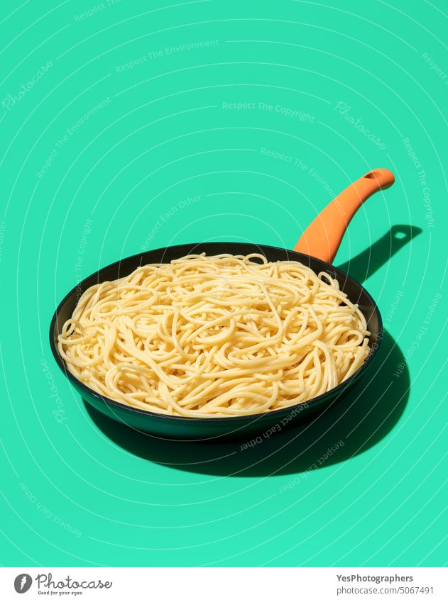 Spaghetti in an iron cast pan isolated on a green background bright carbs color cooking copy space creative cuisine cut out design dinner dish food fresh
